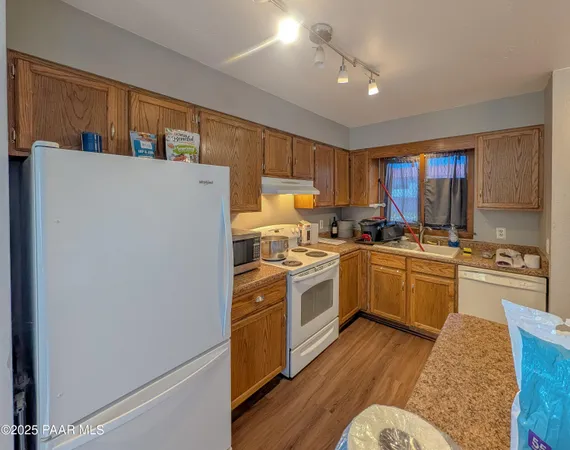 a kitchen with a refrigerator a stove top oven a sink dishwasher and white cabinets with wooden floor