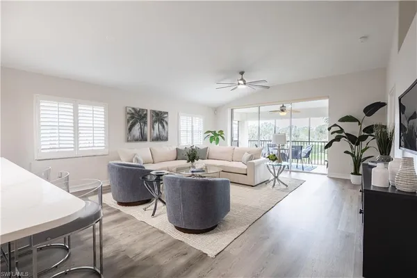 a living room with furniture a large window and wooden floor