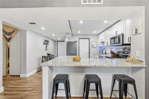 a kitchen with stainless steel appliances granite countertop a table chairs refrigerator and sink