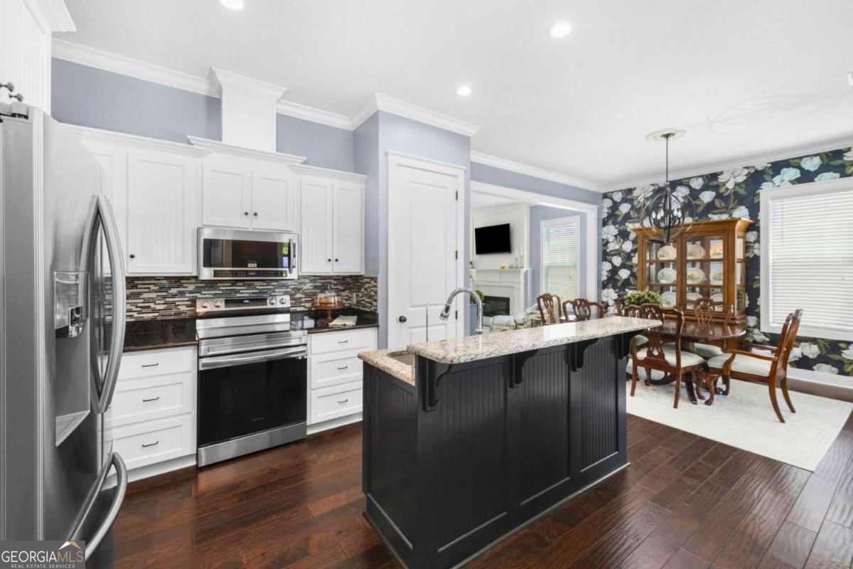 106 Boatsman Way St. Marys, GA 31558 - Photo 10 of 52 a kitchen with stainless steel appliances kitchen island granite countertop a stove top oven a sink dishwasher a dining table and chairs with wooden floor
