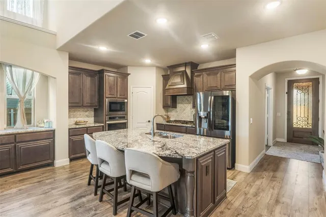 a kitchen with granite countertop kitchen island wooden floor center island and stainless steel appliances