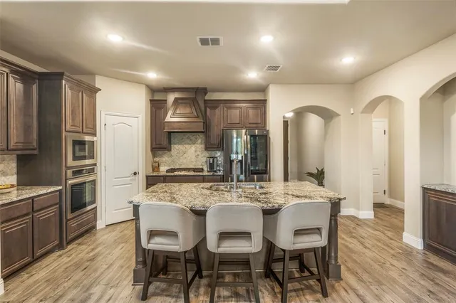 a kitchen with stainless steel appliances kitchen island granite countertop a kitchen island and chairs in it