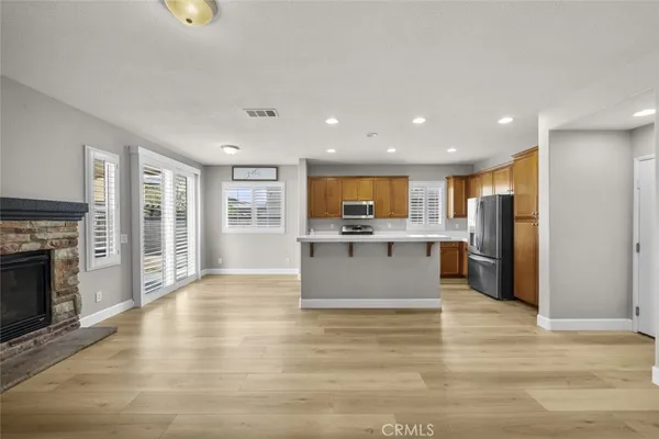 a large kitchen with kitchen island a stove a refrigerator a sink dishwasher with a fireplace and cabinets