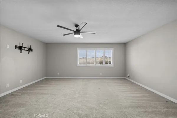 an empty room with a window and a ceiling fan