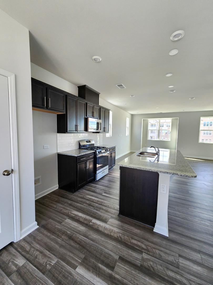 2431 Kasota Lane Raleigh, NC 27610 - Photo 22 of 59 a large kitchen with kitchen island a sink dishwasher a refrigerator and a stove with wooden floor