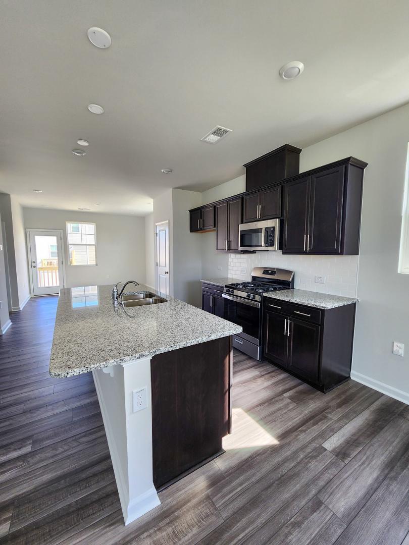 2431 Kasota Lane Raleigh, NC 27610 - Photo 25 of 59 a kitchen with stainless steel appliances kitchen island granite countertop a stove a sink and a refrigerator