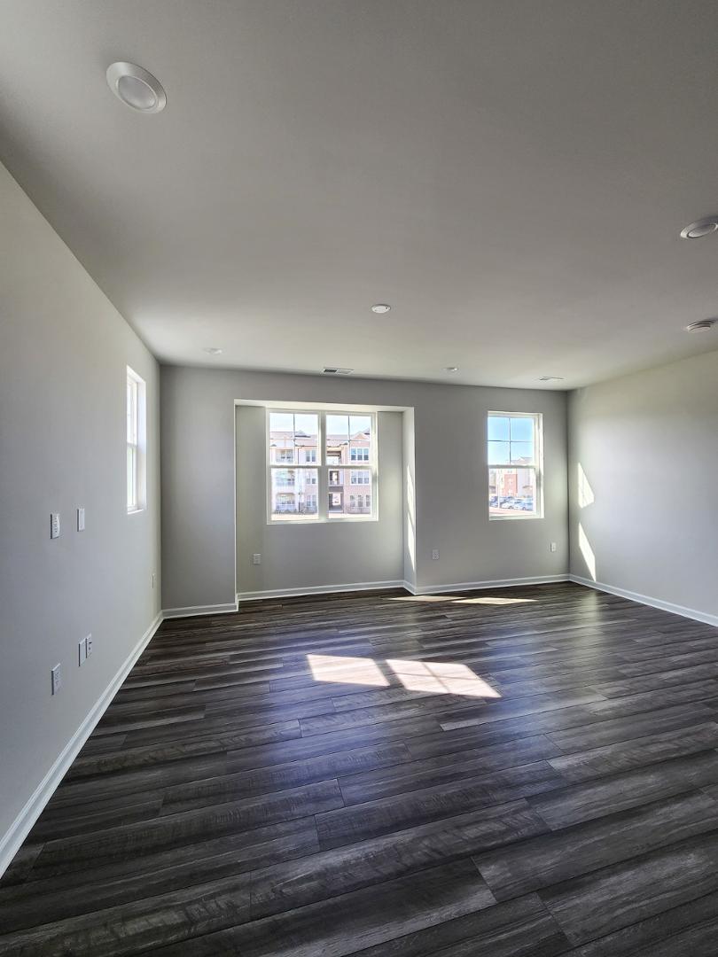 2431 Kasota Lane Raleigh, NC 27610 - Photo 29 of 59 an empty room with wooden floor and windows