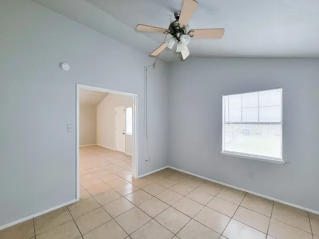 an empty room with chandelier fan and windows