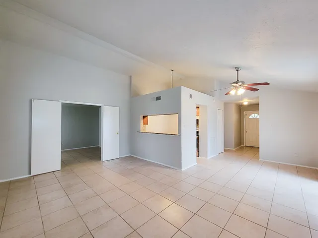 an empty room with kitchen and chandelier fan