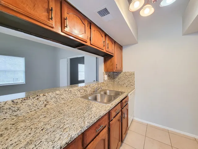 a kitchen with a granite countertop sink and cabinets