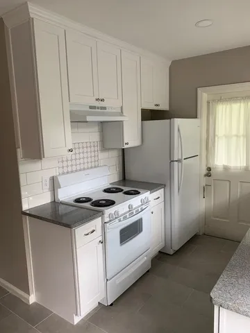 a white stove top oven sitting inside of a kitchen