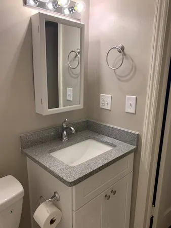 a bathroom with a granite countertop sink and a toilet