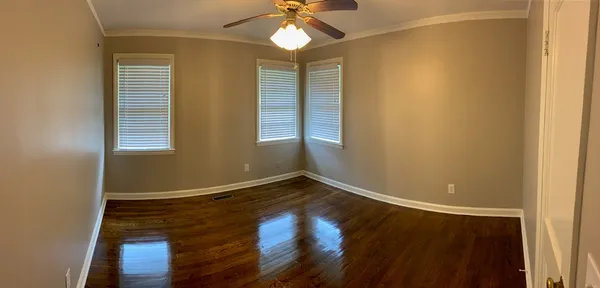 a view of an empty room with window and wooden floor