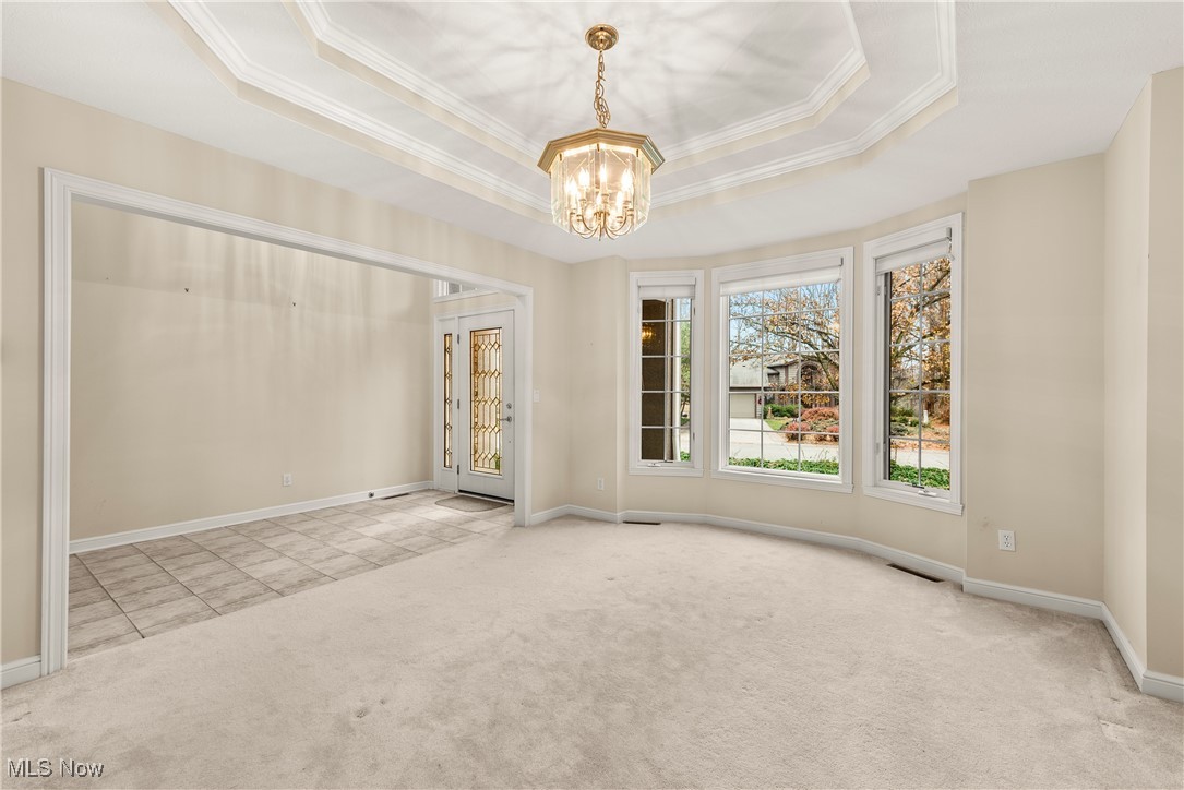 455 Old Reservoir Road Berea, OH 44017 - Photo 10 of 49 Empty room with light carpet, ornamental molding, a raised ceiling, and a notable chandelier