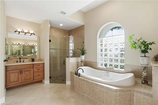 a bathroom with a bathtub a sink a mirror a window and a shower