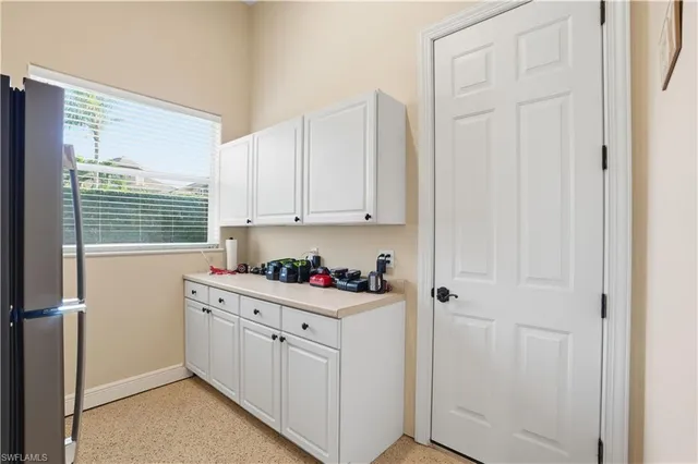 a kitchen with white cabinets and window
