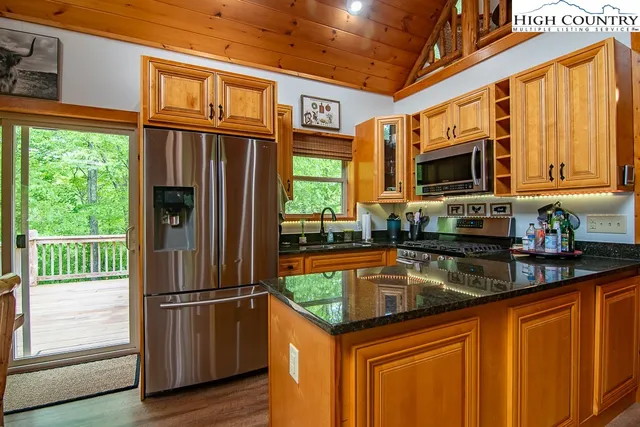 a kitchen with stainless steel appliances granite countertop a refrigerator a sink a stove a microwave and wooden cabinets