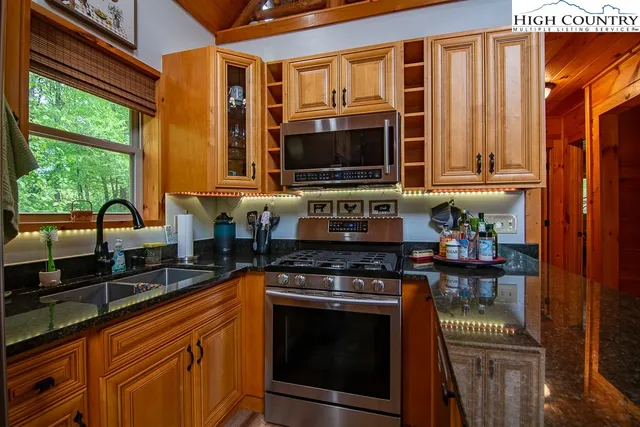 a kitchen with granite countertop a stove top oven cabinetry a sink and a window
