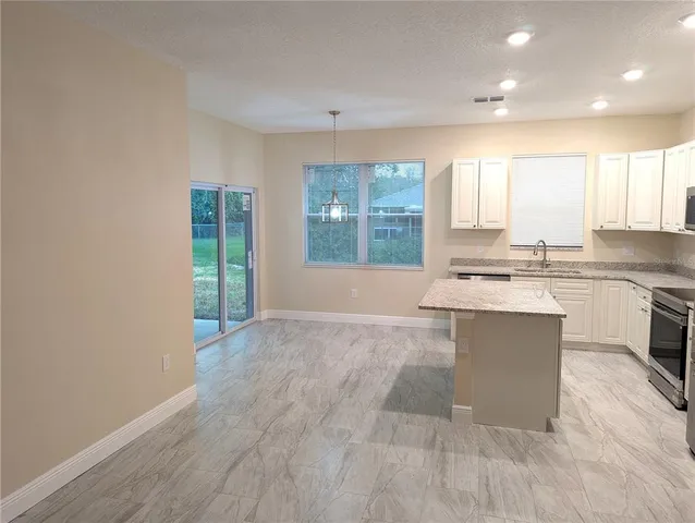 a large kitchen with kitchen island a sink wooden floor and a large window