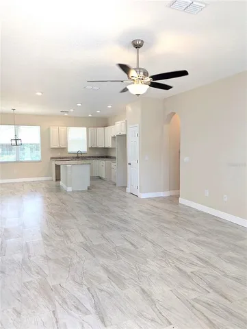 an empty room with wooden floor a ceiling fan and windows