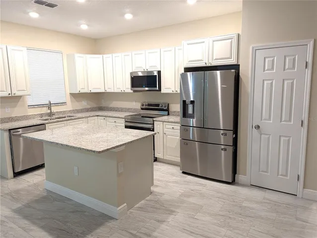 a kitchen with stainless steel appliances granite countertop a refrigerator a stove a sink and a microwave