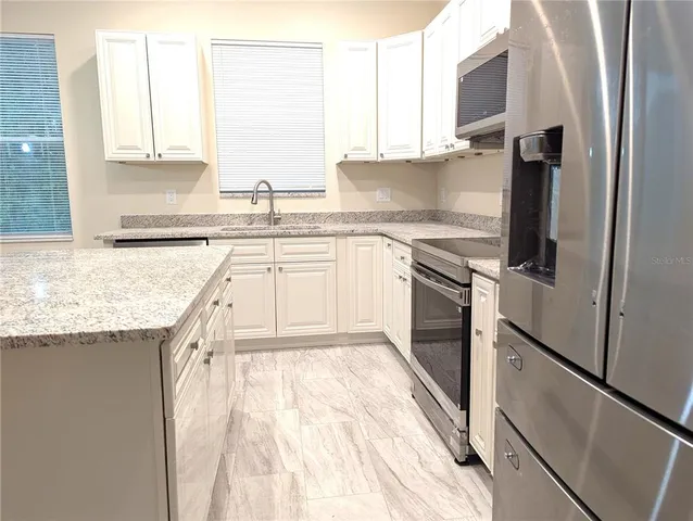 a kitchen with granite countertop a sink stove and refrigerator