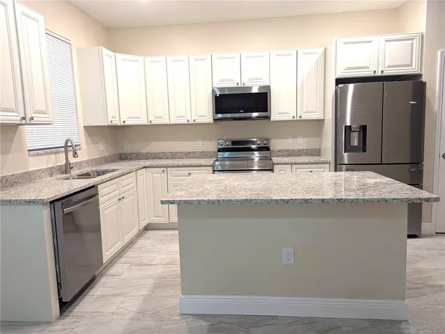 a kitchen with stainless steel appliances granite countertop a stove a sink dishwasher a refrigerator and a microwave