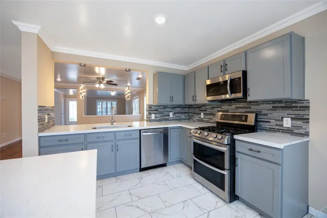 a kitchen with stainless steel appliances granite countertop a stove top oven a sink dishwasher and a microwave oven on the blue kitchen countertops