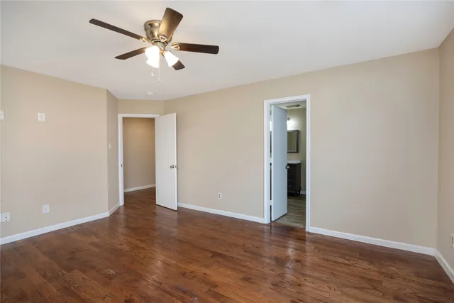 an empty room with wooden floor and a ceiling fan