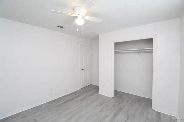 an empty room with wooden floor and ceiling fan