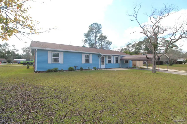 a front view of house with yard and trees in the background