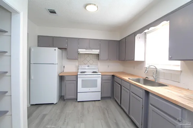 a kitchen with a sink white cabinets and white appliances