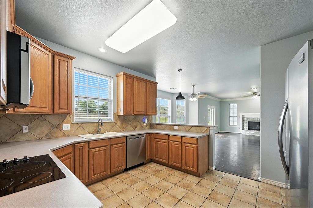 6659 Meadow Ridge Circle Nevada, TX 75173 - Photo 11 of 27 Kitchen featuring stainless steel appliances, a peninsula, light countertops, tasteful backsplash, and a ceiling fan