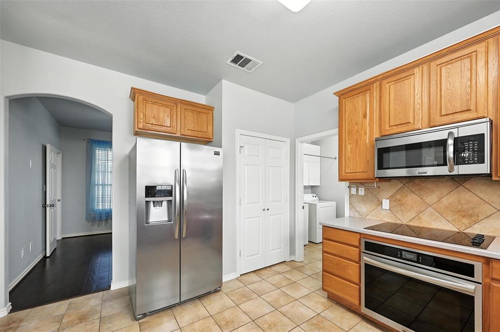 6659 Meadow Ridge Circle Nevada, TX 75173 - Photo 12 of 27 Kitchen with stainless steel appliances, independent washer and dryer, arched walkways, backsplash, and light countertops