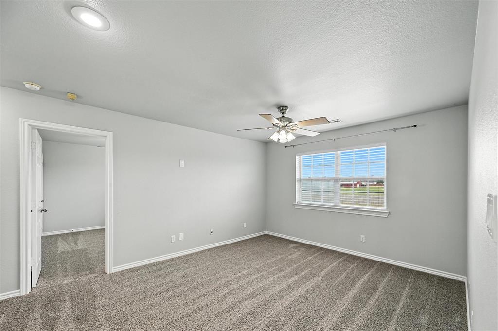 6659 Meadow Ridge Circle Nevada, TX 75173 - Photo 15 of 27 Unfurnished room with dark carpet, a ceiling fan, a smoke detector, and a textured ceiling