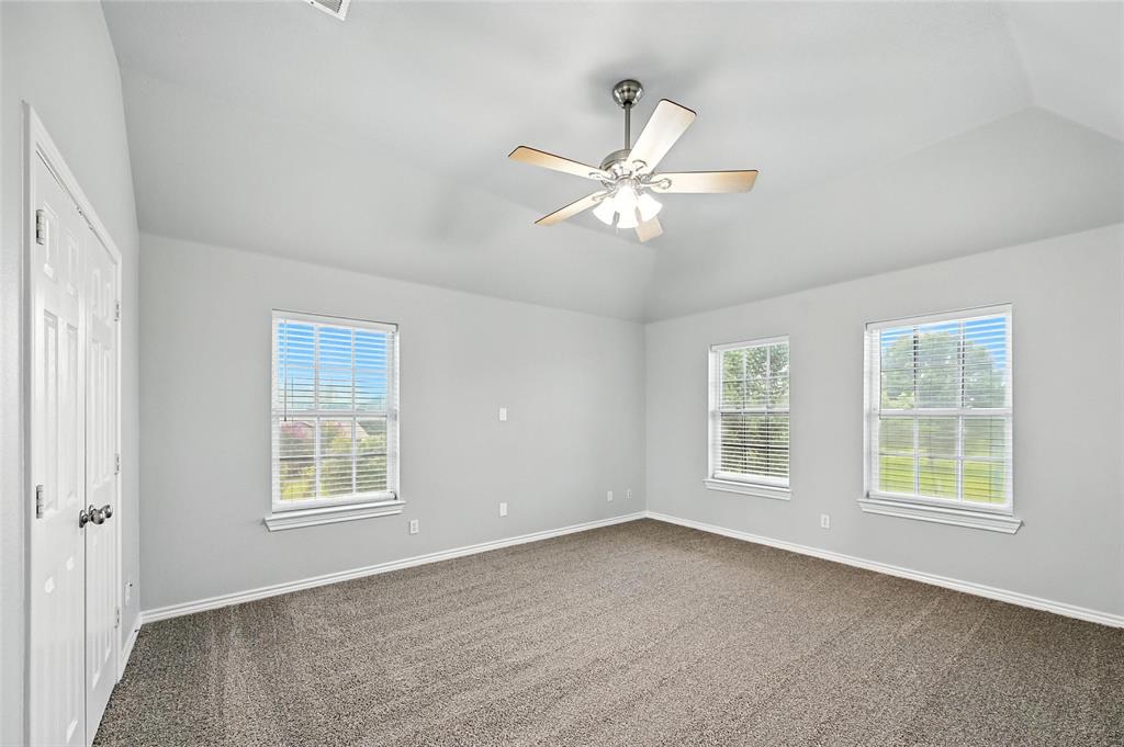6659 Meadow Ridge Circle Nevada, TX 75173 - Photo 22 of 27 Unfurnished bedroom with lofted ceiling, dark carpet, and a ceiling fan