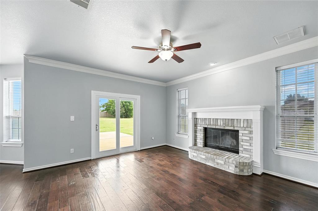 6659 Meadow Ridge Circle Nevada, TX 75173 - Photo 7 of 27 Unfurnished living room with ceiling fan, hardwood / wood-style flooring, a fireplace, and crown molding