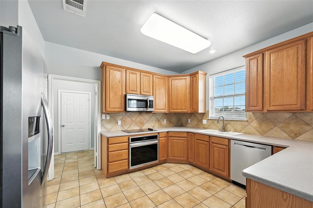6659 Meadow Ridge Circle Nevada, TX 75173 - Photo 10 of 27 Kitchen with appliances with stainless steel finishes, decorative backsplash, light tile patterned floors, and light countertops