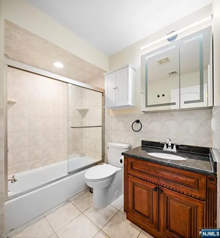 a bathroom with a granite countertop sink a toilet a mirror and shower