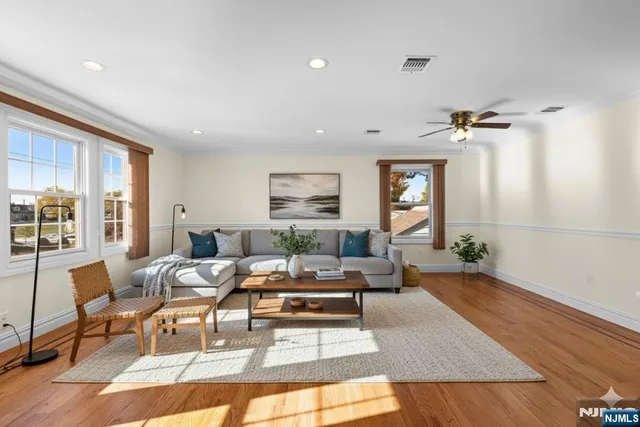 a living room with furniture large window and wooden floor