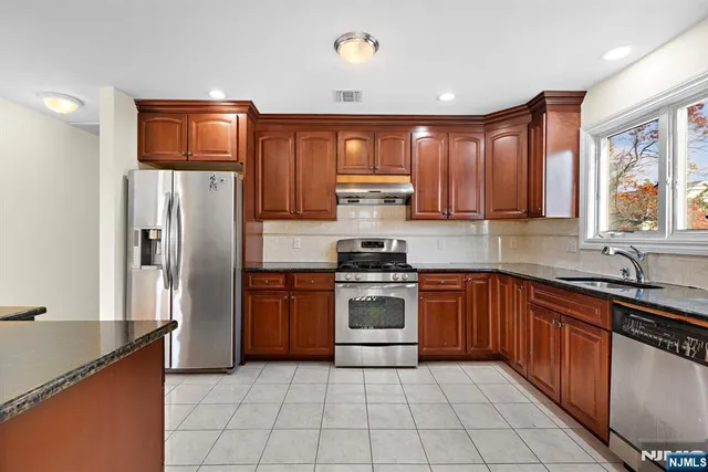 a kitchen with stainless steel appliances granite countertop a refrigerator and a stove top oven