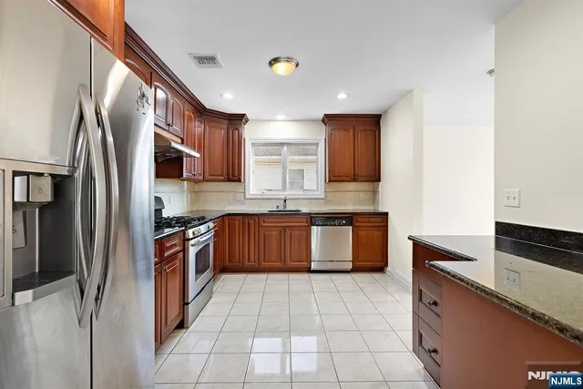 a large kitchen with stainless steel appliances granite countertop a stove a sink dishwasher a refrigerator and a microwave