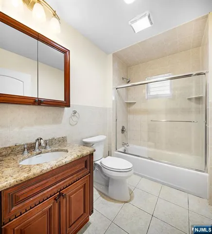 a bathroom with a granite countertop sink a toilet and bathtub