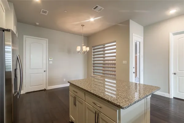 an empty room with kitchen view and wooden floor