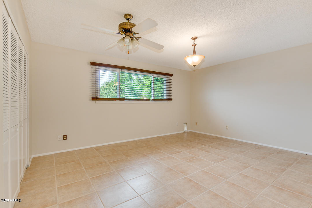 3931 West Rancho Drive Phoenix, AZ 85019 - Photo 15 of 32 an empty room with a chandelier fan and windows