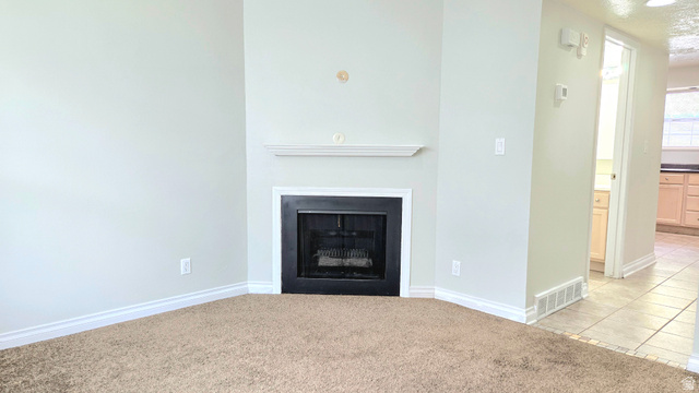 8732 Fairoaks Circle Sandy, UT 84070 - Photo 8 of 18 Unfurnished living room with light carpet, a fireplace, and light tile patterned floors