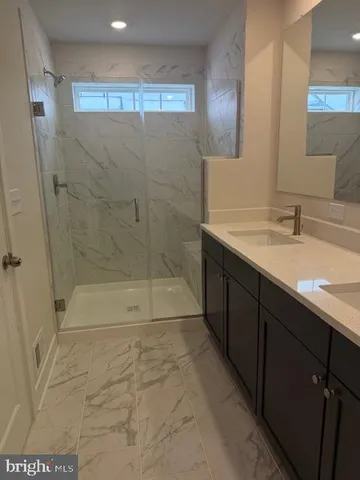 a bathroom with a granite countertop sink a mirror and shower