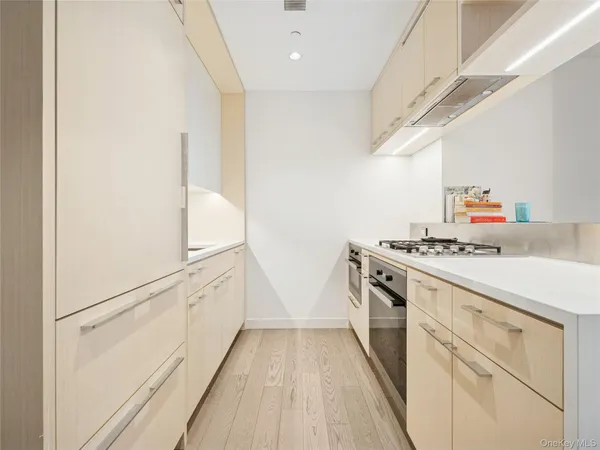 a kitchen with a sink and white cabinets with wooden floor