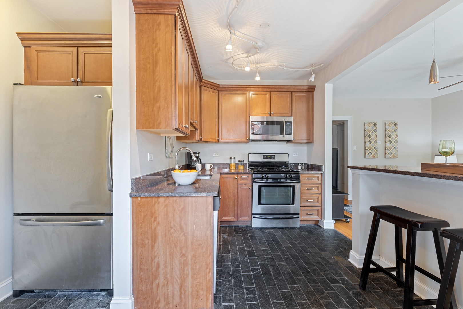 1905 West Winona Street, Unit 2 Chicago, IL 60640 - Photo 11 of 18 a kitchen with stainless steel appliances a stove a refrigerator a sink a dining table and chairs