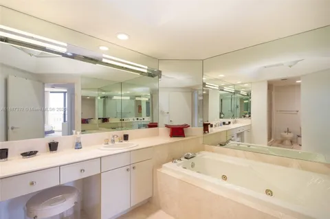a bathroom with a tub a sink double vanity and a mirror
